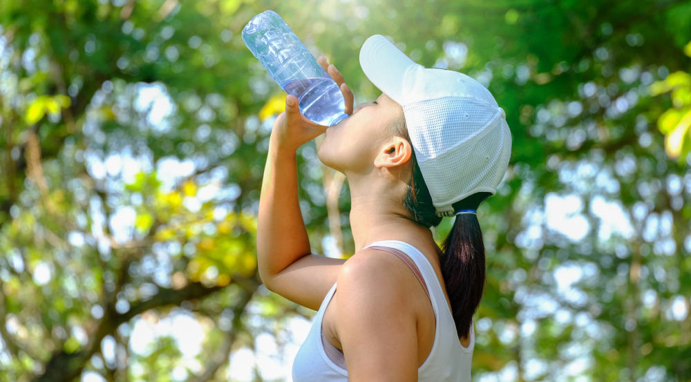 dziewczyna pijąca wodę mineralną w trakcie treningu